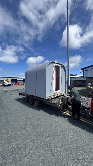 Made-to-order garden office pod strapped to a trailer leaving the workshop
