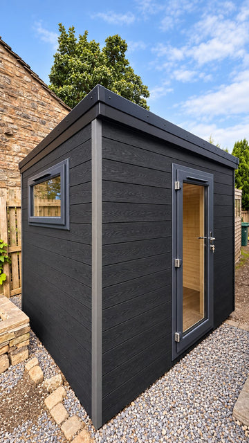 Composite-clad garden office on a level gravel and slab base beside a stone wall